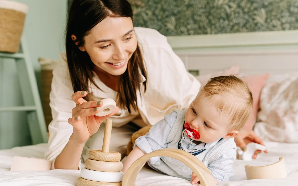 Uśmiechnięta mama pokazuje dziecku drewnianą piramidkę z krążków