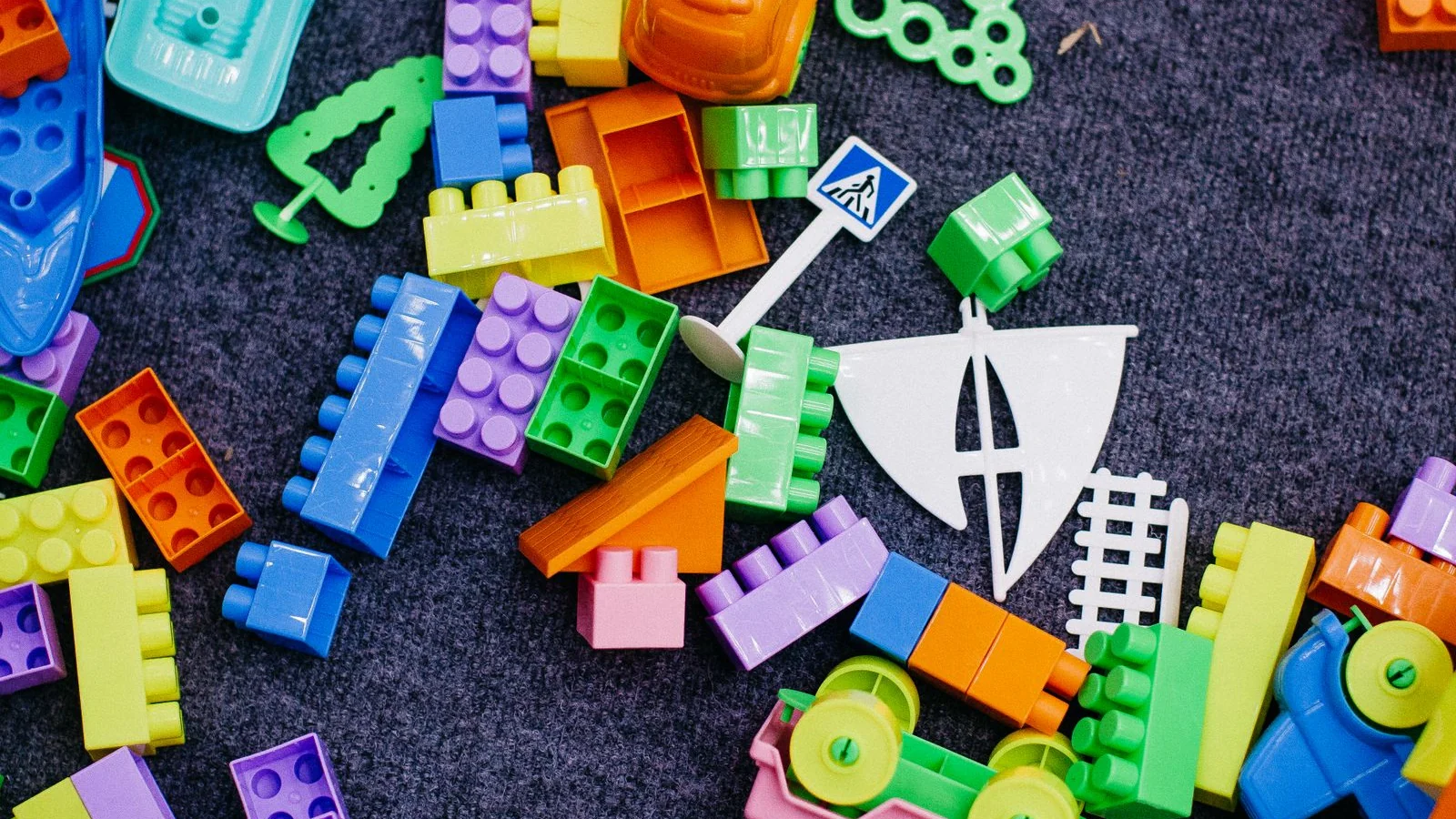 Sterta jaskrawych plastikowych klocków na ciemnym dywanie