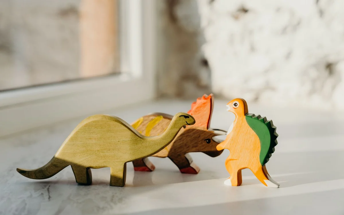 Przechodzone drewniane figurki dinozaurów na parapecie