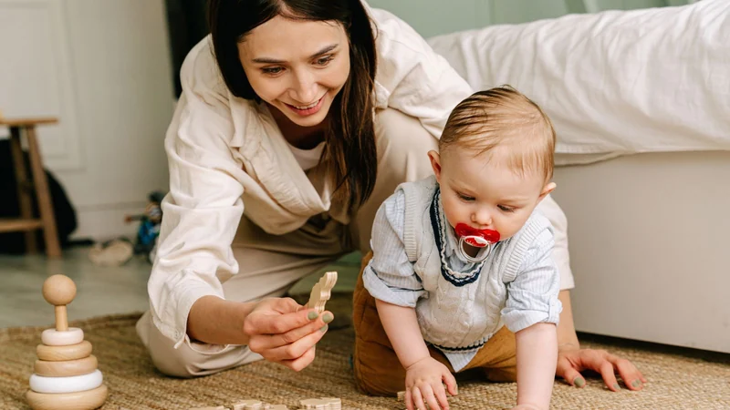 Mama i niemowlę bawią się drewnianymi zabawkami na macie