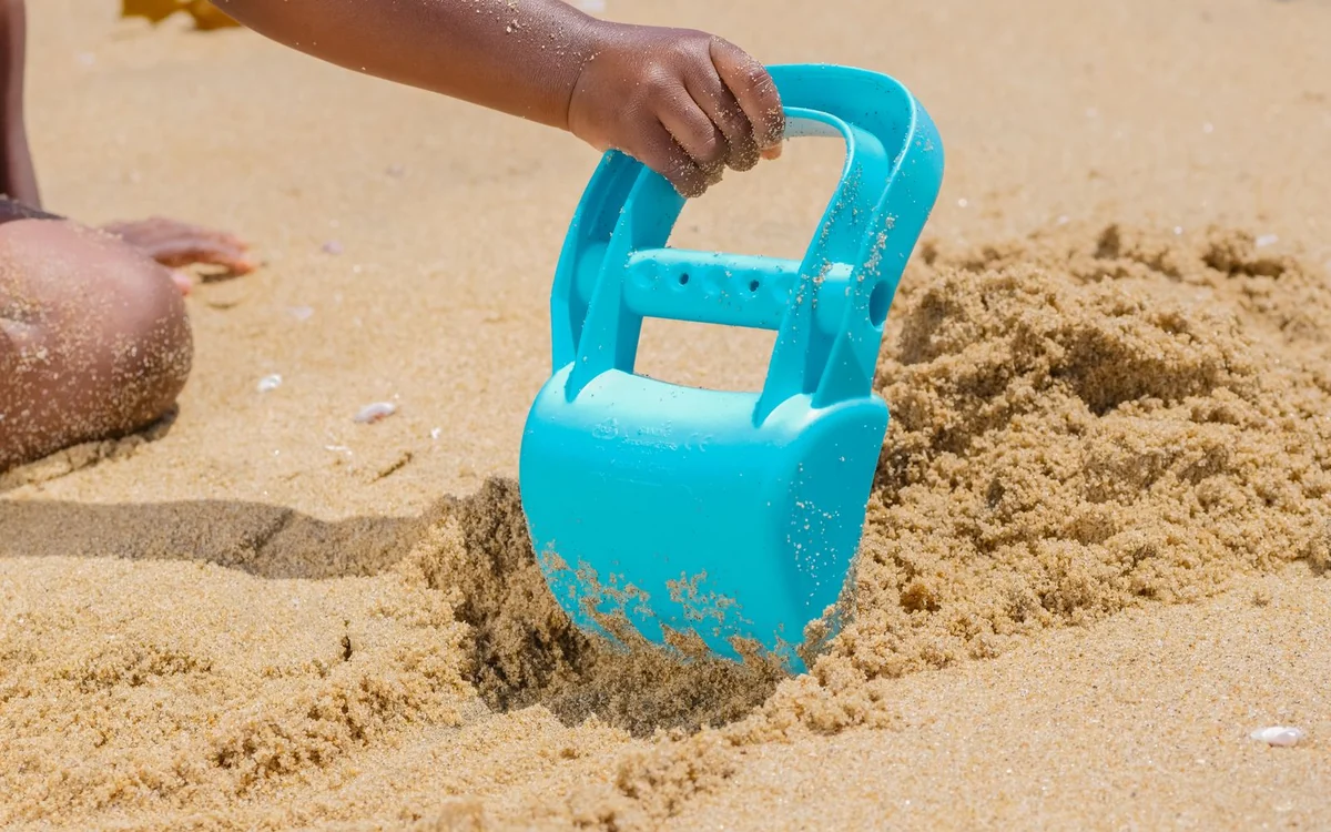 Niebieska łopatka do piasku wbita w piasek na plaży